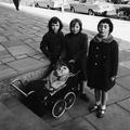 Three young girls stand on the street with their Guy Fawkes effigy in a pram. Image preview