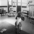A young child in a baby bouncer walking frame photographed at the John F Kennedy Centre for training and education of children with severe disability, West Ham Image preview